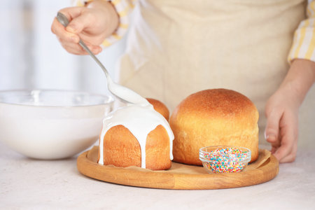Woman putting glaze on Easter cakes at light table, closeup