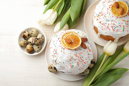 Beautiful Easter cakes, eggs and tulips on white table, flat lay
