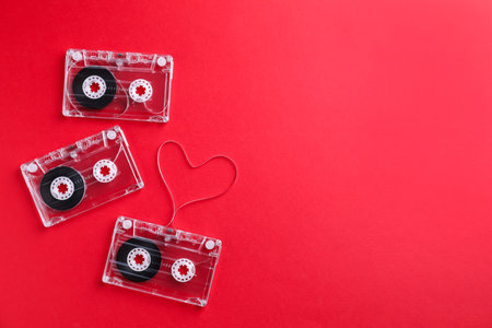 Music cassettes and heart made with tape on red background, flat lay. Space for textの写真素材