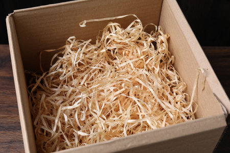 Shredded paper filling in cardboard box on wooden table, closeupの写真素材
