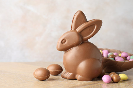 Chocolate Easter bunny and egg on wooden table against light gray background, closeup. Space for...