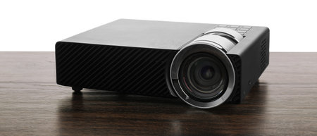 Modern video projector on wooden table against white background
