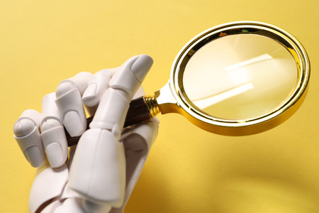 Mannequin hand with magnifying glass on yellow background, closeupの写真素材