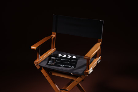 Film director's chair with clapperboard on dark brown backgroundの写真素材