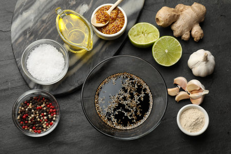 Soy sauce and other different ingredients for marinade on dark gray textured table, flat lay
