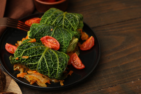 Stuffed cabbage rolls with vegetables served on wooden table, closeup. Space for text
