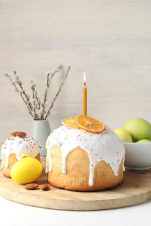 Tasty Easter cakes, painted eggs and willow branches on white wooden table, closeup