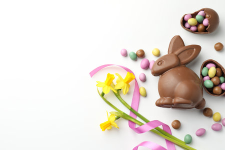 Chocolate Easter bunny, flowers, ribbon and eggs on white background, flat lay. Space for textの写真素材
