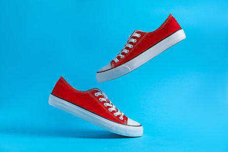 Pair of stylish sneakers in air on light blue backgroundの写真素材