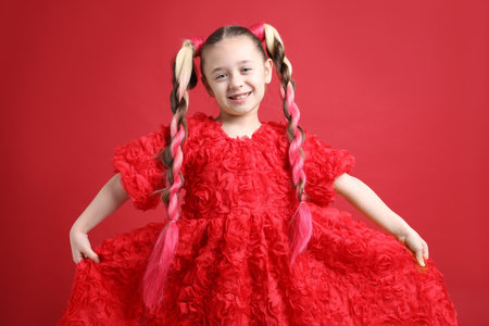 Cute girl with stylish pigtail braids on red backgroundの写真素材