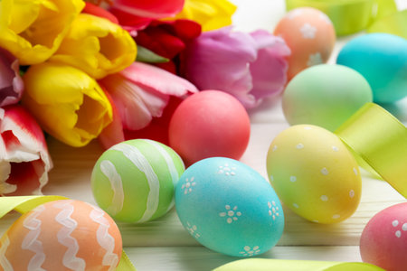 Painted Easter eggs and beautiful tulips on white wooden table, closeupの写真素材