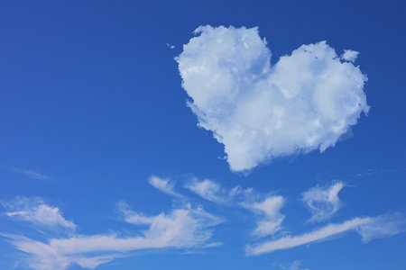 Cute fluffy heart-shaped cloud in blue sky