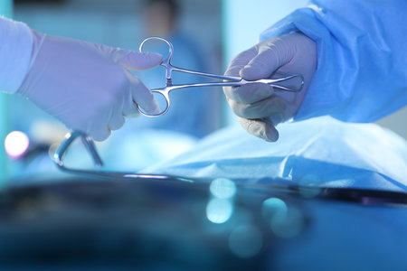 Professional surgeons with medical instruments performing operation in surgery room, closeup