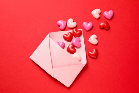Love. Envelope with decorative hearts on red background, flat lay