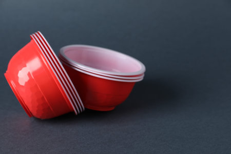 Plastic packaging. Disposable bowls on gray background, closeup with space for textの写真素材