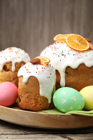 Delicious decorated Easter cakes and eggs on wooden table, closeup