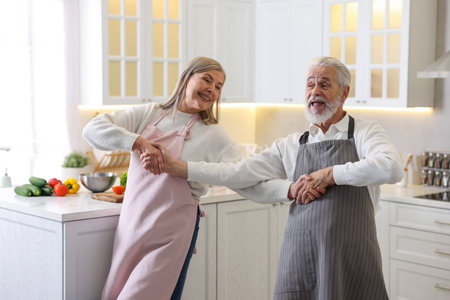 Happy senior couple dancing while cooking in kitchenの写真素材