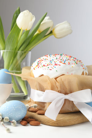 Tasty Easter cake, painted eggs and tulips on white wooden table, closeup