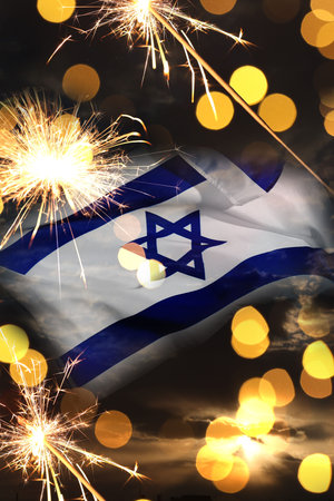 Flag of Israel, burning sparklers and bokeh lights, double exposure with sunset sky. National holiday celebrationの写真素材