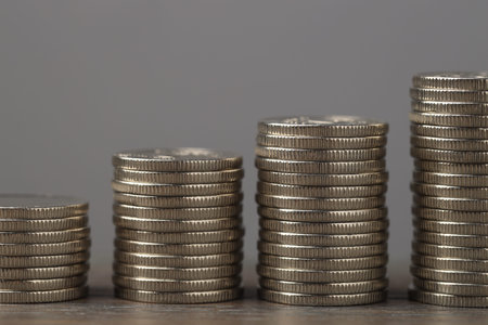 Stacks of coins on wooden table against gray background, closeup