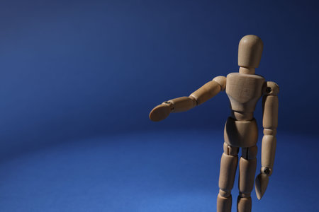 One wooden mannequin standing on blue background, closeup. Space for textの写真素材