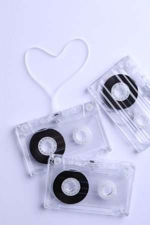 Music cassettes and heart made with tape on white background, flat lay