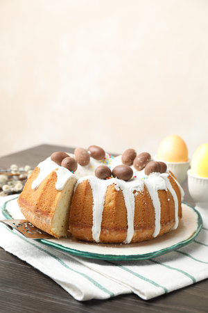 Delicious Easter cake with painted eggs and willow branches on wooden table indoors, closeup