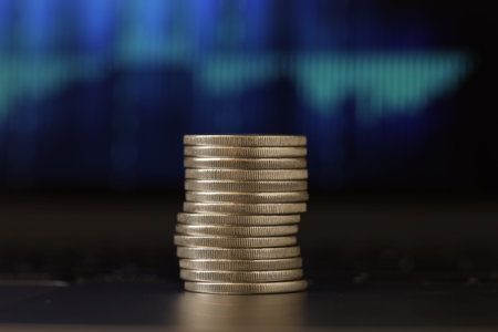 Stack of coins on laptop against blurred background, closeup