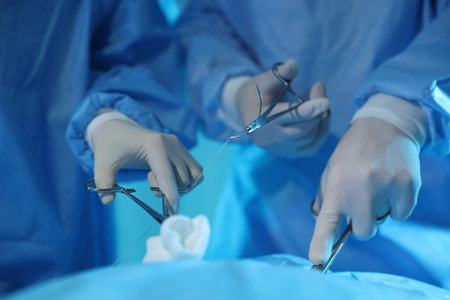 Professional surgeons with medical instruments performing operation in surgery room, closeup