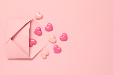 Love. Envelope with decorative hearts on pink background, flat lay