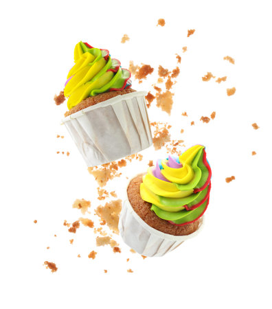 Yummy cupcakes with colorful cream flying in air on white backgroundの写真素材