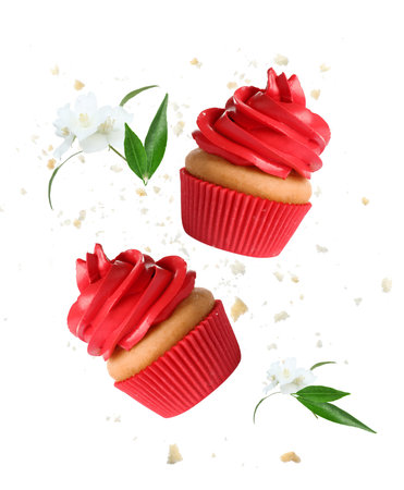 Delicious cupcakes with red cream flying in air on white backgroundの写真素材