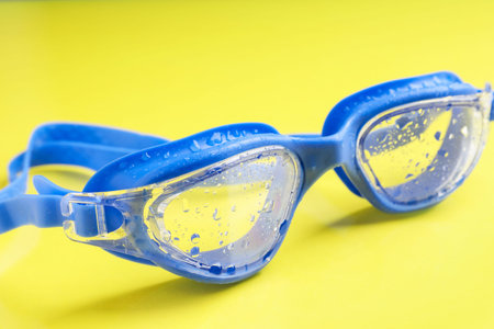 Swimming goggles with water drops on yellow background, closeupの写真素材