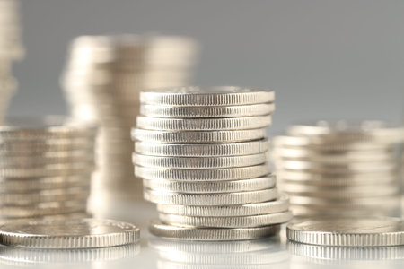 Many stacked coins on light background, closeup