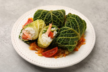 Stuffed cabbage rolls served with vegetables on grey background, closeup