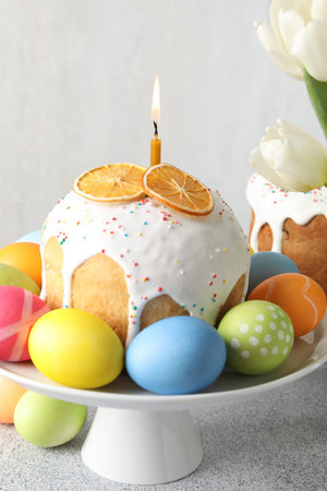 Tasty Easter cakes and painted eggs on light grey table, closeup