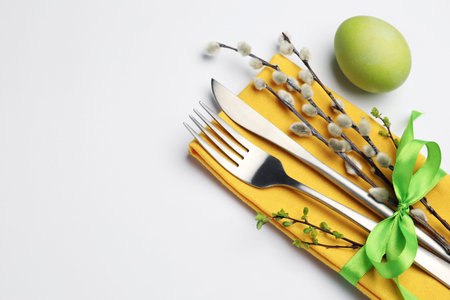Easter table setting. Beautiful silverware with willow branches and painted egg isolated on white
