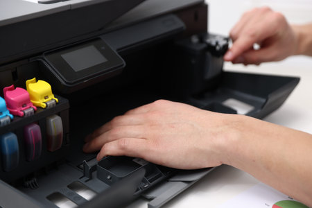 Man working with printer at white desk indoors, closeup