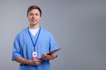 Portrait of medical assistant with tablet on grey background, space for text