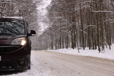 Modern car parked near road and trees on winter day, space for text