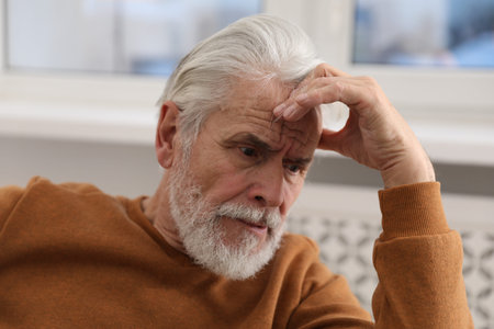 Amnesia. Senior man trying to remember something at home
