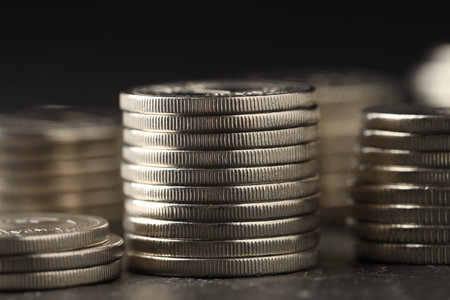 Many stacked coins on table against blurred background, closeup