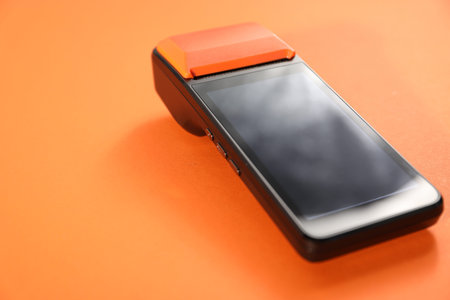 One payment terminal on orange background, closeup. Space for text