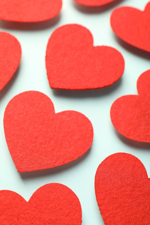 Love. Red decorative hearts on light blue background, closeup