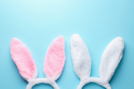 Happy Easter. Cute headbands with bunny ears on light blue background, flat lay. Space for text