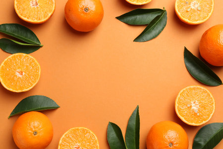 Frame made of fresh ripe tangerines and leaves on orange background, flat lay. Space for text