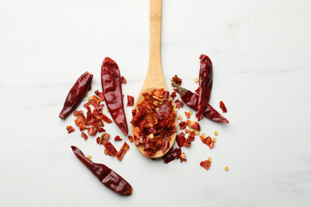 Red chili peppers in wooden spoon on white marble table, flat layの写真素材