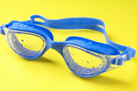 Swimming goggles with water drops on yellow background, closeupの写真素材