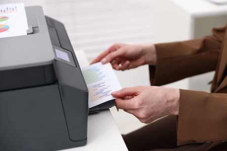 Woman using printer at white desk indoors, closeup