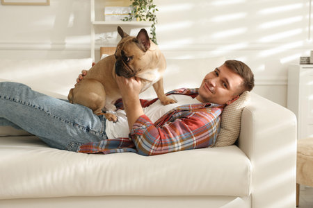 Young man with his cute dog relaxing on sofa at homeの写真素材